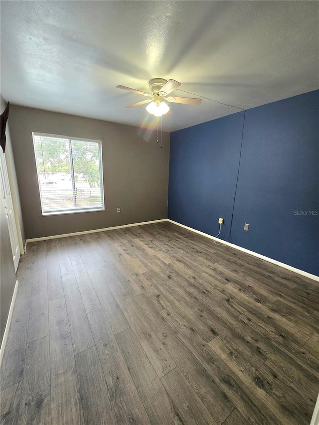 empty room with ceiling fan, dark hardwood / wood-style flooring, and a textured ceiling