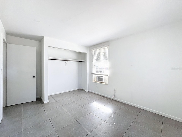 unfurnished bedroom featuring cooling unit, light tile patterned flooring, and a closet