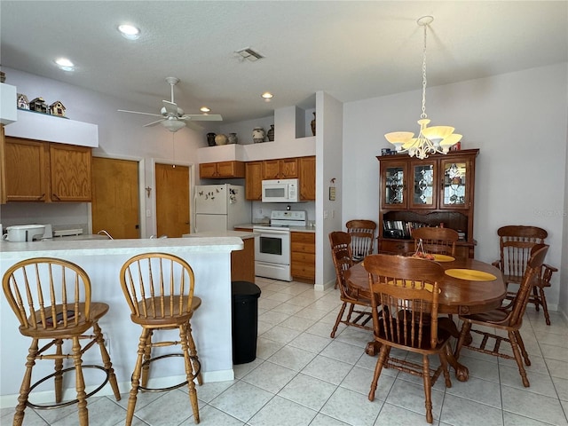 kitchen with ceiling fan with notable chandelier, white appliances, kitchen peninsula, and light tile patterned floors