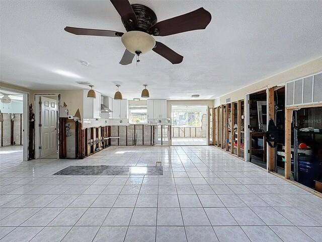 interior space featuring light tile patterned floors, a textured ceiling, and ceiling fan