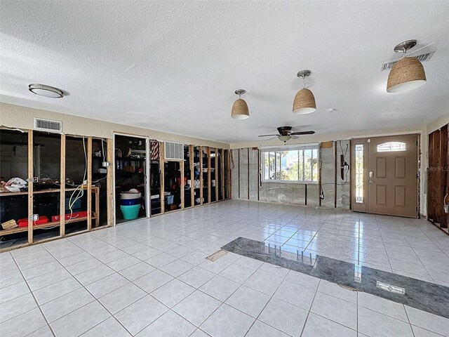 misc room featuring ceiling fan, light tile patterned floors, and a textured ceiling