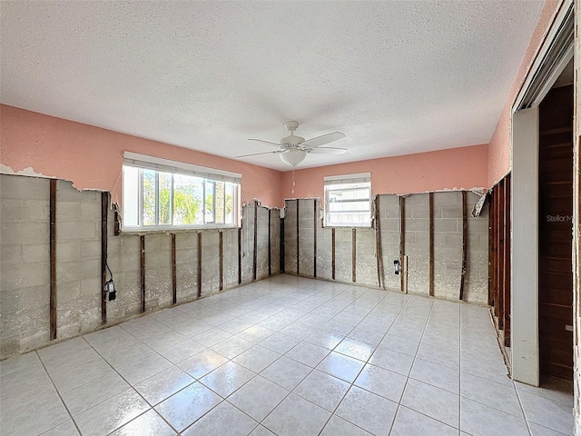 unfurnished room with ceiling fan, light tile patterned floors, and a textured ceiling