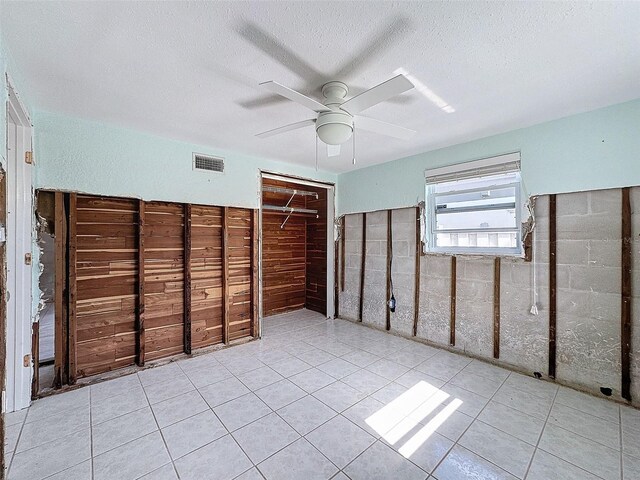 unfurnished bedroom featuring ceiling fan, light tile patterned floors, and a textured ceiling