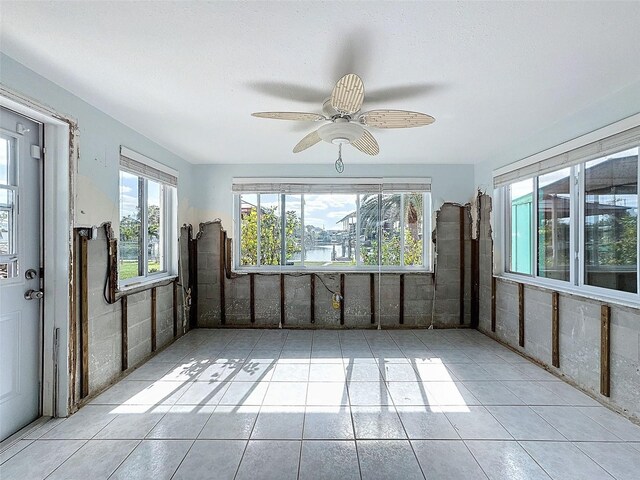 tiled spare room featuring ceiling fan and a healthy amount of sunlight