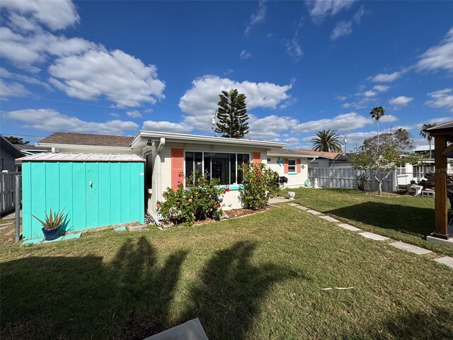 rear view of house featuring a storage unit and a yard