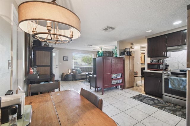 dining area featuring ceiling fan with notable chandelier, light tile patterned floors, and a textured ceiling