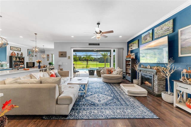 living room with a fireplace, dark hardwood / wood-style flooring, crown molding, and ceiling fan with notable chandelier