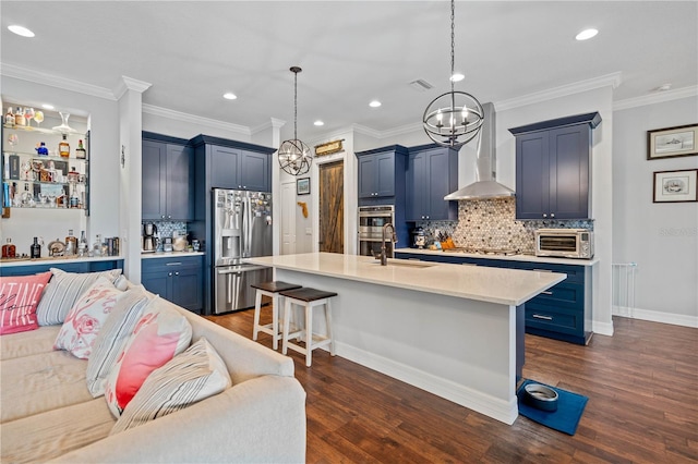 kitchen with backsplash, wall chimney range hood, sink, appliances with stainless steel finishes, and decorative light fixtures