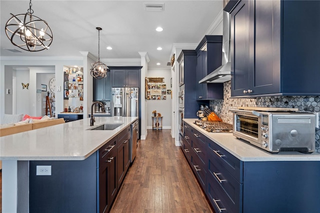 kitchen with appliances with stainless steel finishes, decorative light fixtures, a center island with sink, and sink