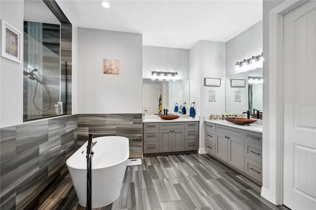 bathroom with a tub to relax in, vanity, and tile walls