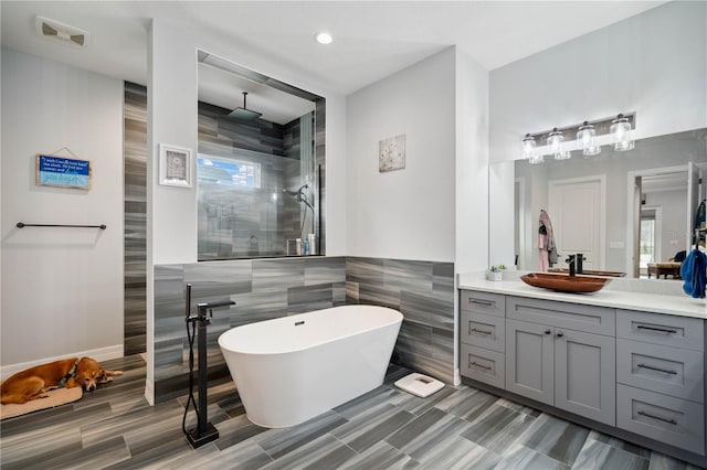 bathroom with vanity, plus walk in shower, and tile walls