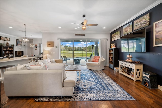 living room featuring ceiling fan with notable chandelier, dark hardwood / wood-style flooring, and ornamental molding