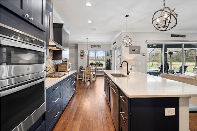 kitchen with sink, tasteful backsplash, pendant lighting, a center island with sink, and appliances with stainless steel finishes