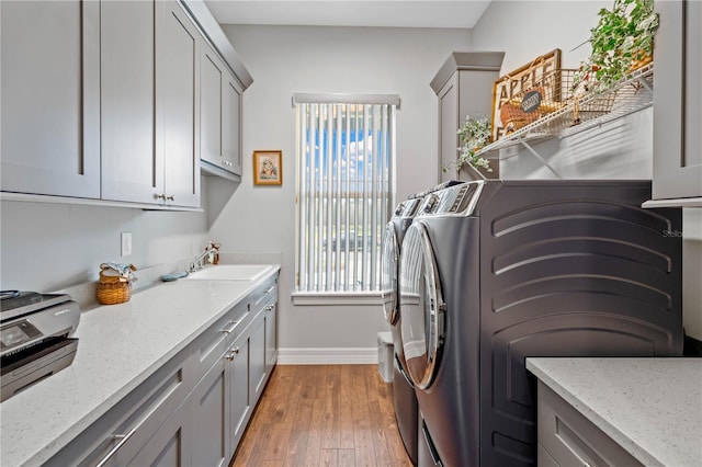 laundry room featuring light wood-type flooring, washer and clothes dryer, and sink