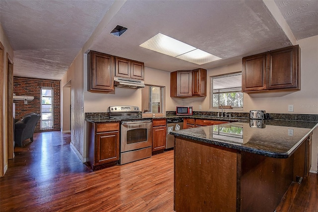 kitchen with hardwood / wood-style floors, a textured ceiling, and appliances with stainless steel finishes