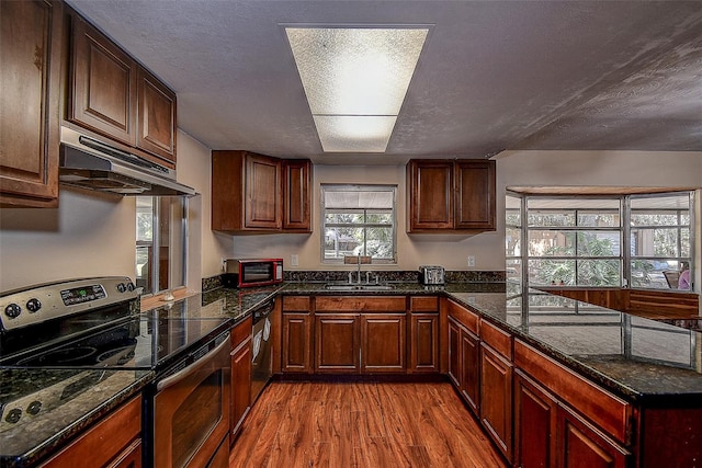 kitchen with dark stone countertops, electric range, light hardwood / wood-style flooring, and a textured ceiling