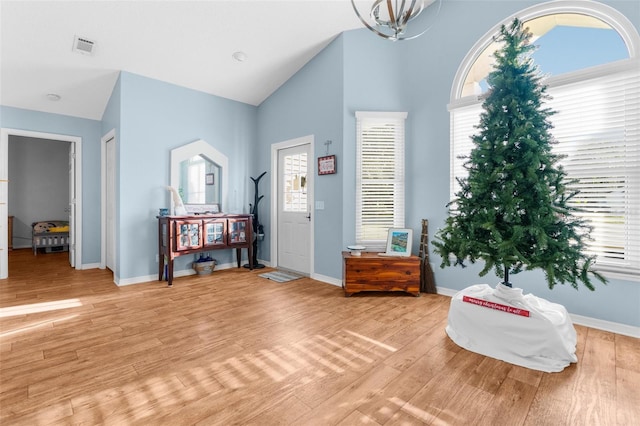 sitting room with light wood-type flooring, high vaulted ceiling, and a notable chandelier