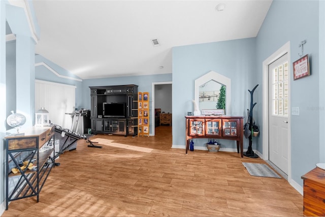 workout room with light wood-type flooring, visible vents, lofted ceiling, and baseboards