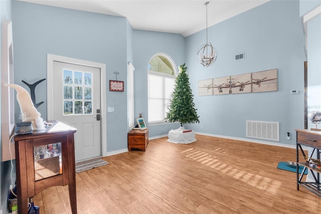 entryway featuring light wood-type flooring, visible vents, baseboards, and an inviting chandelier