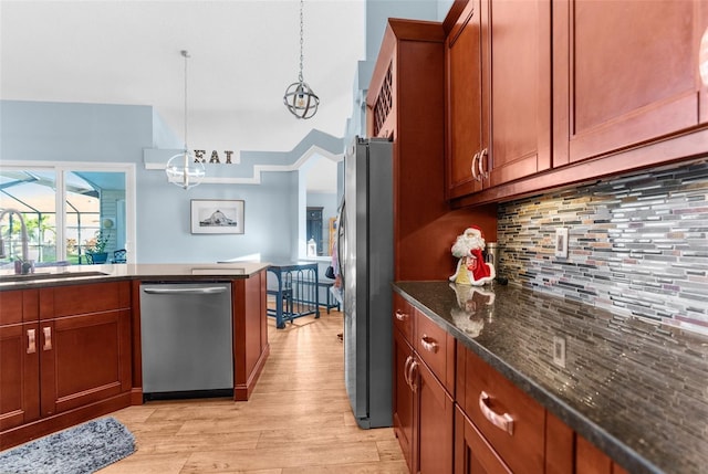 kitchen featuring a sink, hanging light fixtures, stainless steel appliances, tasteful backsplash, and light wood-type flooring