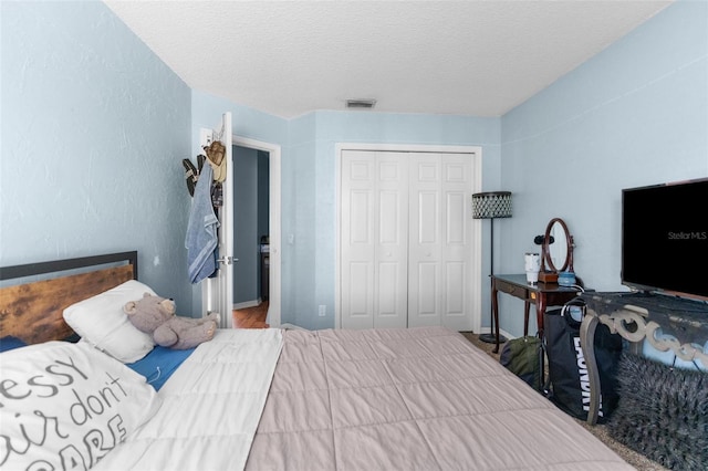 bedroom with visible vents, a textured ceiling, and a closet