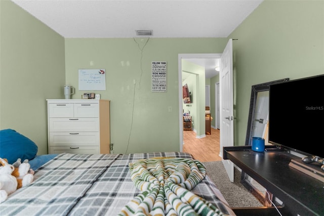 bedroom with light wood-style floors and visible vents