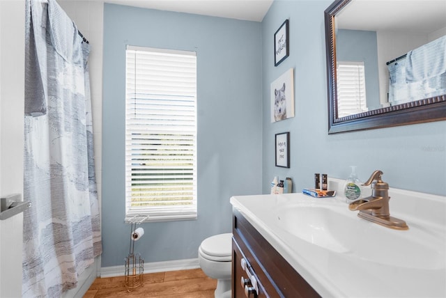 full bathroom featuring curtained shower, baseboards, toilet, wood finished floors, and vanity