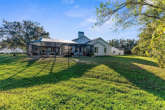 rear view of property with glass enclosure, a yard, and a chimney