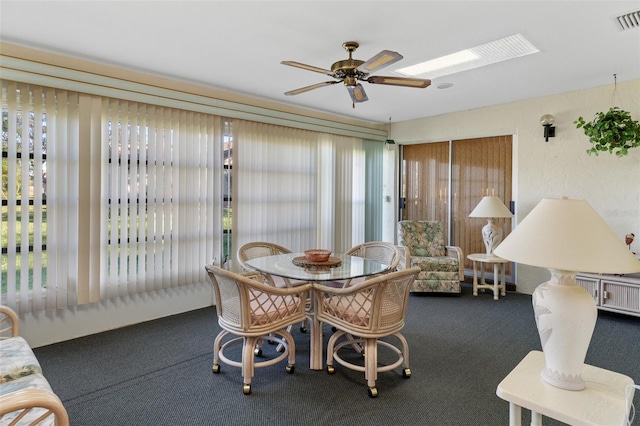 carpeted dining area featuring a skylight, ceiling fan, and a healthy amount of sunlight