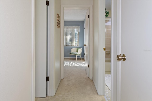 hallway with a textured ceiling and light colored carpet