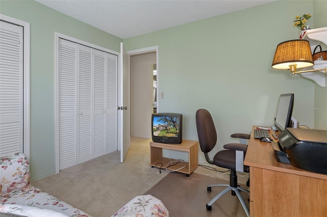 carpeted home office featuring a textured ceiling