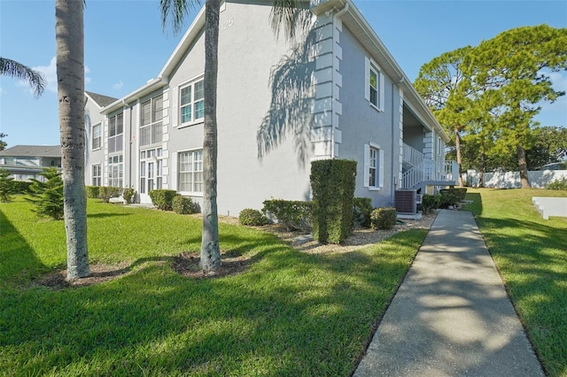 view of side of home with a lawn and central air condition unit