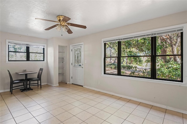 empty room featuring ceiling fan, a healthy amount of sunlight, and light tile patterned floors