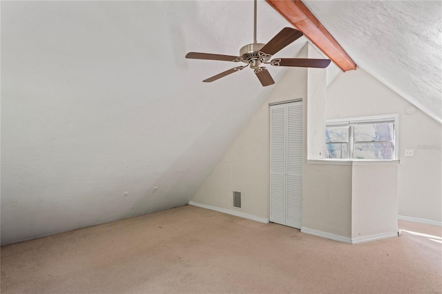 additional living space with vaulted ceiling with beams, ceiling fan, and light colored carpet