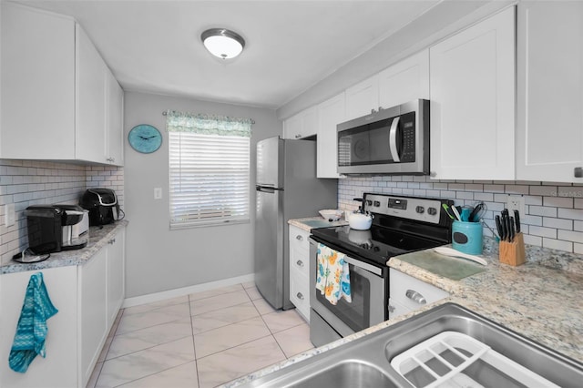 kitchen with white cabinets, backsplash, stainless steel appliances, and light stone counters