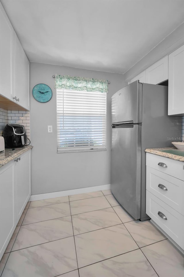 kitchen featuring decorative backsplash, white cabinetry, and light stone countertops