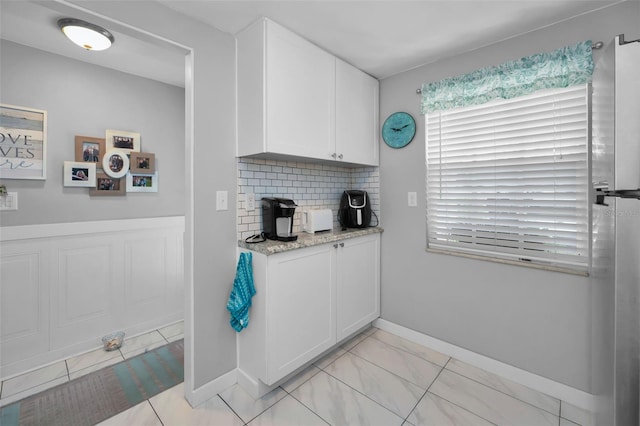 kitchen featuring white cabinets, tasteful backsplash, and light stone countertops