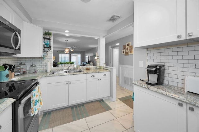 kitchen featuring white cabinetry, stainless steel appliances, light tile patterned floors, and tasteful backsplash