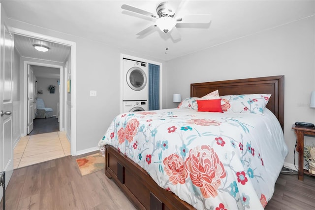 bedroom featuring ceiling fan, stacked washing maching and dryer, and light wood-type flooring