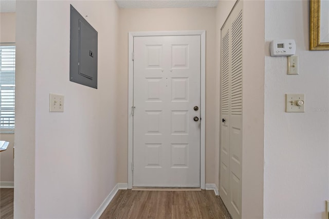 doorway to outside with electric panel, a textured ceiling, and hardwood / wood-style flooring