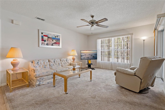 living room with ceiling fan, light colored carpet, and a textured ceiling