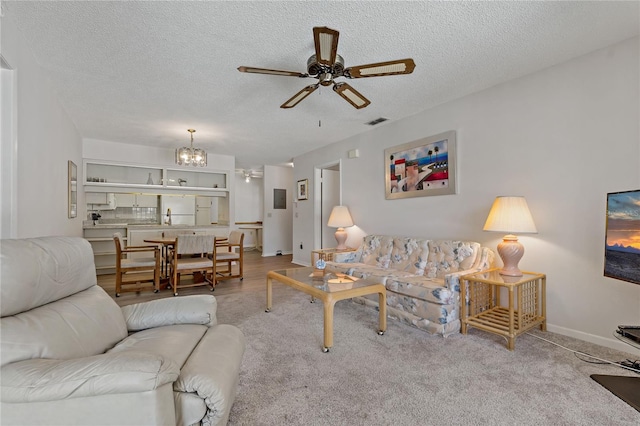 carpeted living room featuring a textured ceiling and ceiling fan with notable chandelier