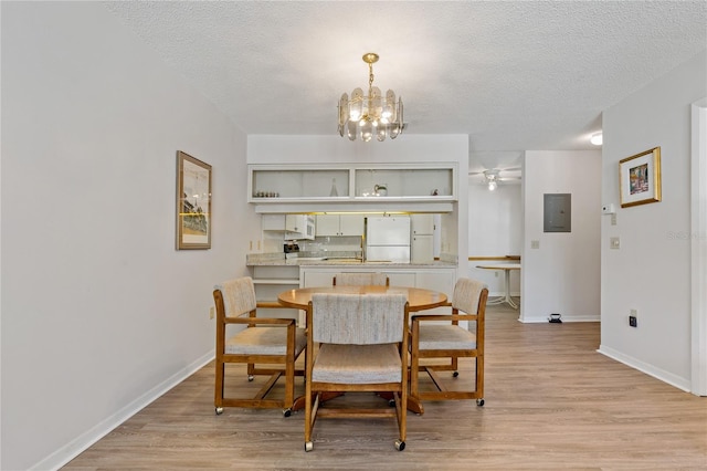 dining area with a chandelier, a textured ceiling, light hardwood / wood-style floors, and electric panel