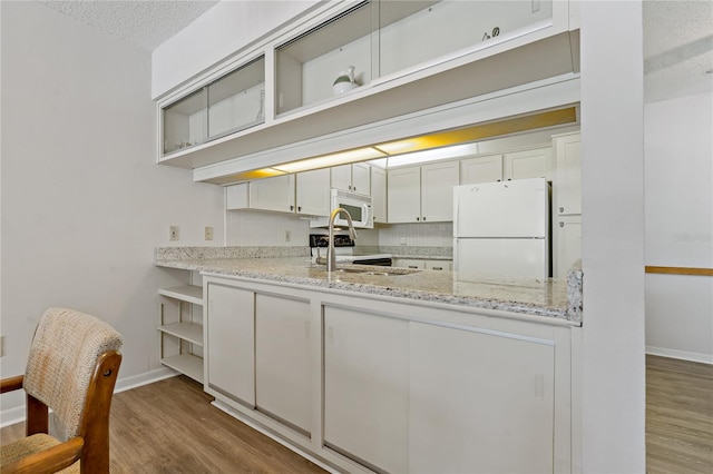 kitchen featuring light stone countertops, dark hardwood / wood-style flooring, a textured ceiling, white appliances, and white cabinetry