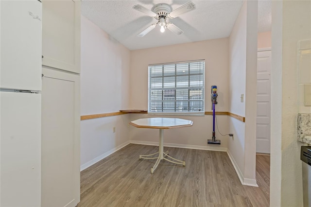 dining space with a textured ceiling, light hardwood / wood-style floors, and ceiling fan