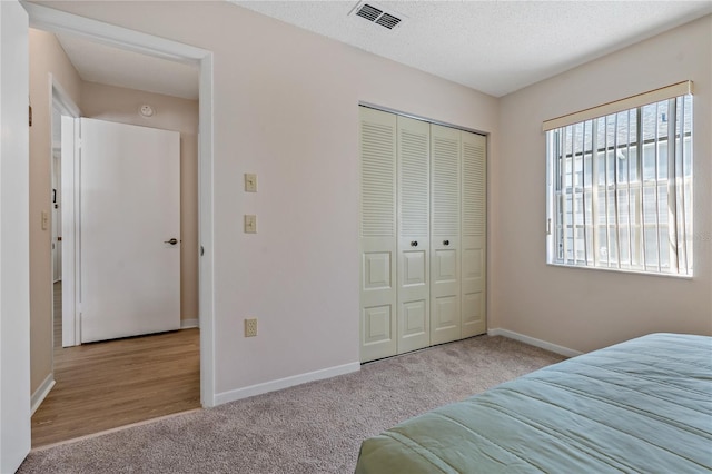 unfurnished bedroom with a textured ceiling, light colored carpet, and a closet