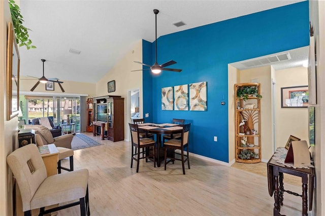 dining space featuring ceiling fan, light wood-type flooring, and high vaulted ceiling