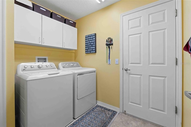 laundry area featuring separate washer and dryer, light tile patterned floors, cabinets, and a textured ceiling