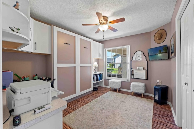 interior space featuring ceiling fan, dark hardwood / wood-style flooring, and a textured ceiling