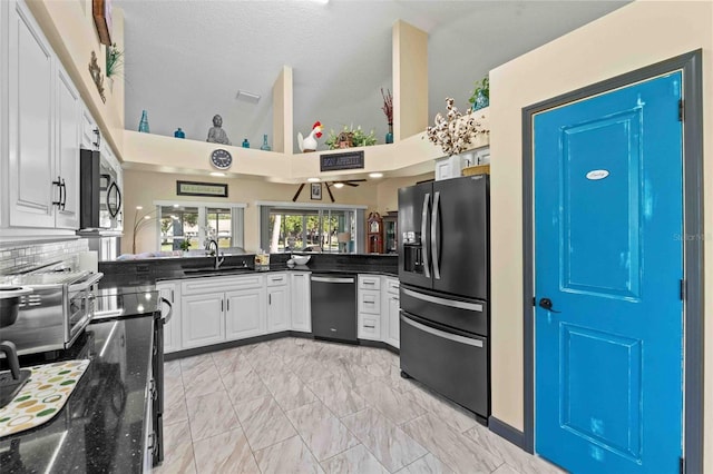 kitchen with kitchen peninsula, appliances with stainless steel finishes, high vaulted ceiling, and white cabinetry